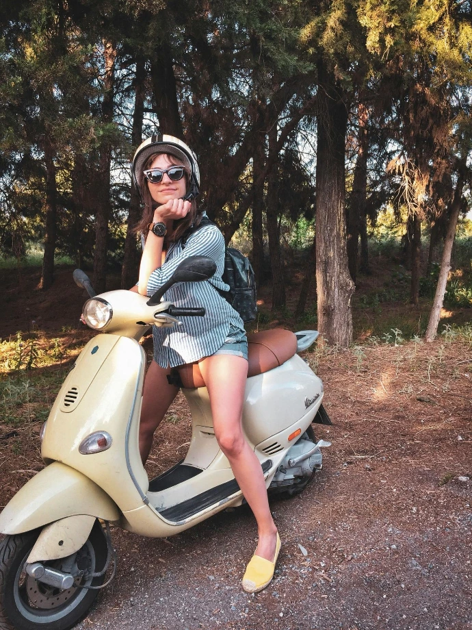 Dame aan het chillen op een Vespa in de natuur